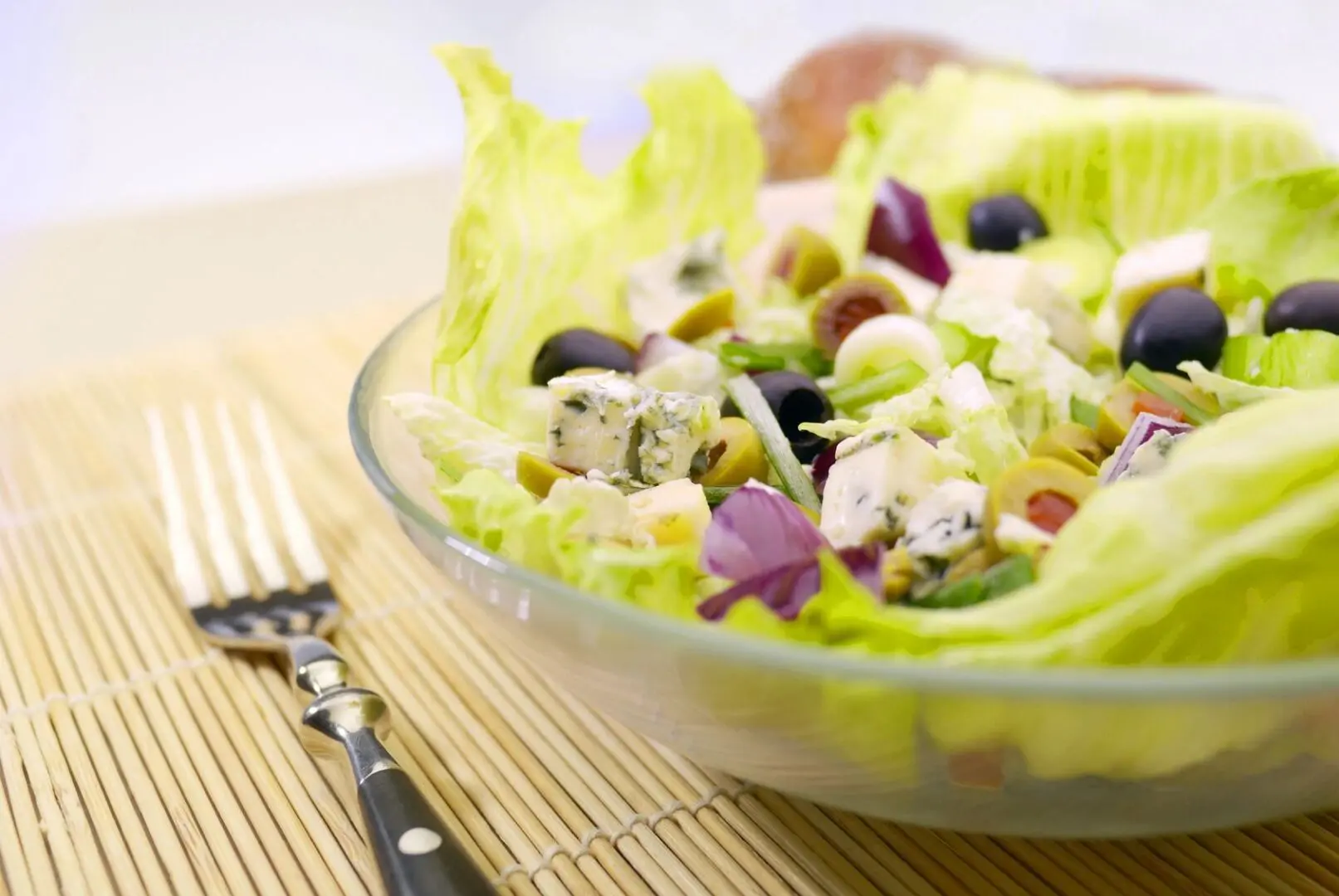 A salad in a bowl with fork and napkin.