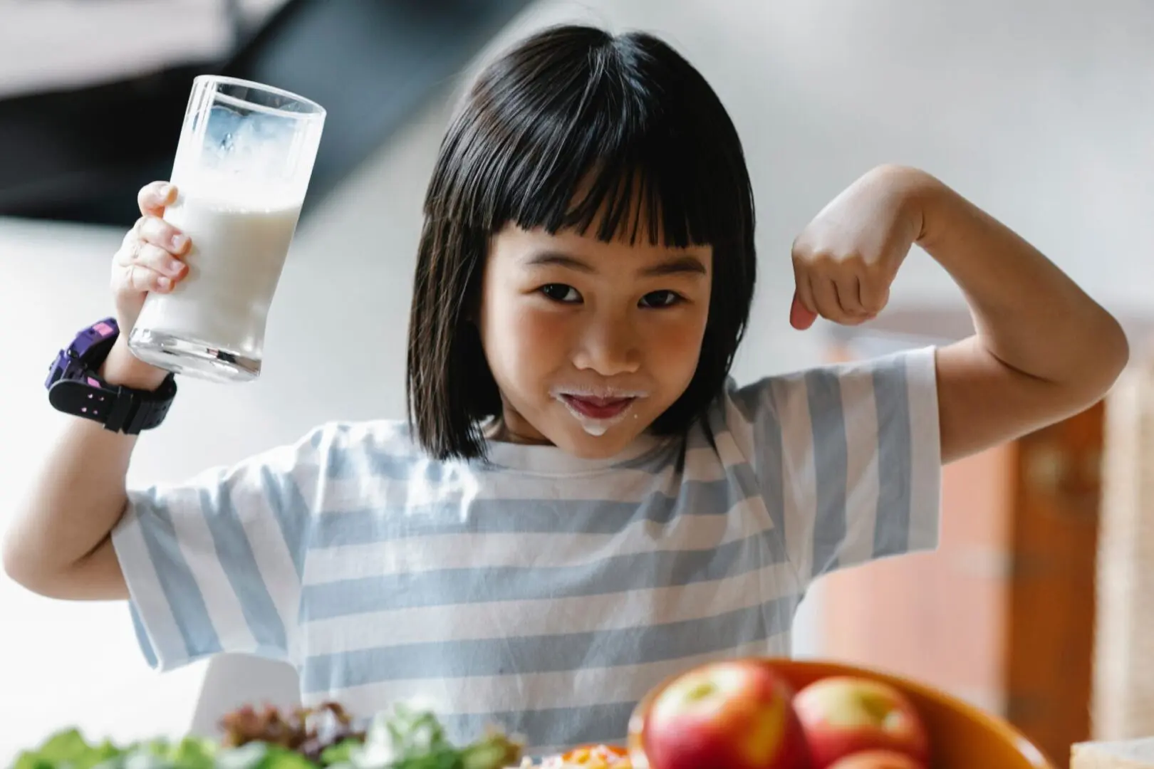 A little girl sitting at the table with some food.