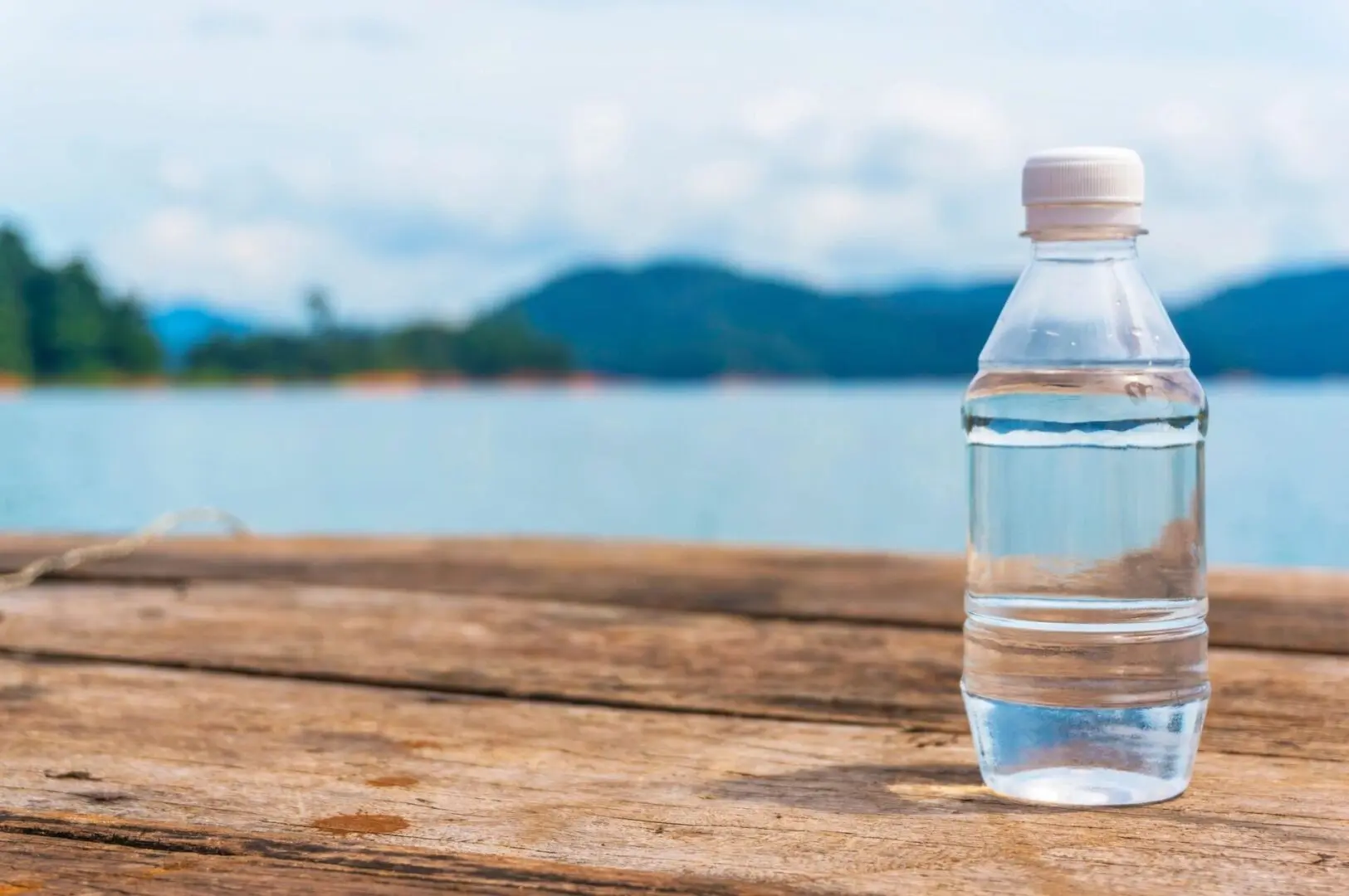 A bottle of water sitting on top of a wooden table.